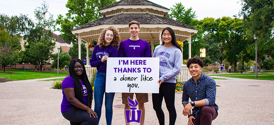 Students pose in front of the gazebo with a sign that says 