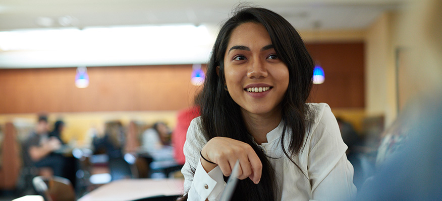 Smiling female student sits with friends in lounge area on WSU campus.