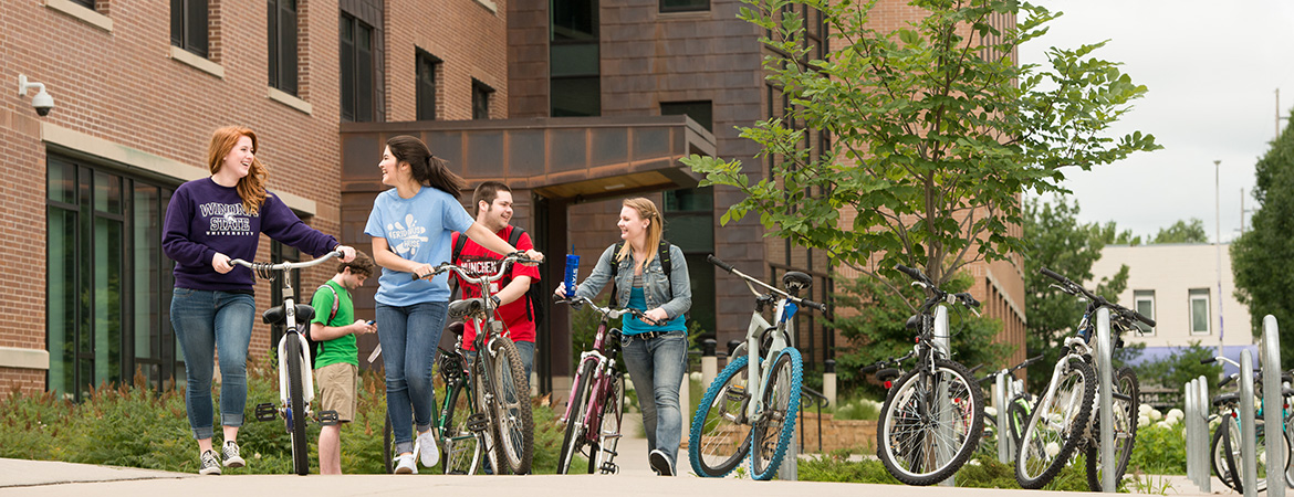 Students walk away from Kirkland Hall with their bikes.