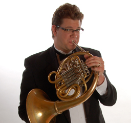 Professor Corey Henke plays a French horn.