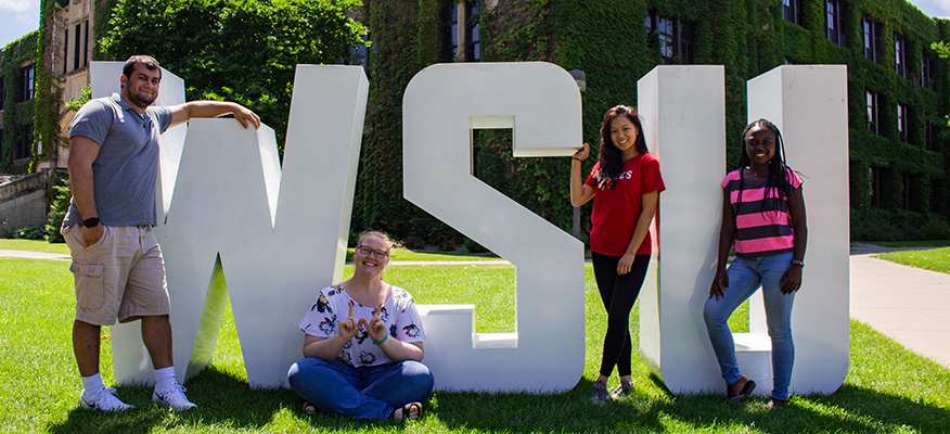 A group of students pose in front of WSU Letters outside Somesen Hall.