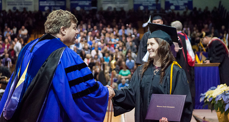 Graduated student shaking President Scott Olson's hand