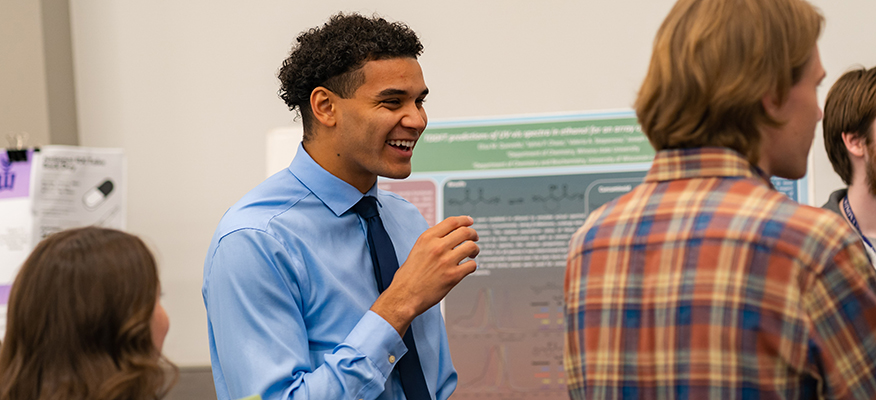 Three students have a conversation at the Research Celebration. 